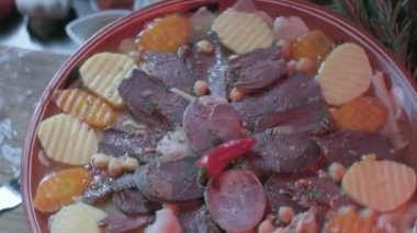 Close-up of national Kazakh dish Beshbarmak made of veggies, dough and horsemeat served in deep clay dish with hot red pepper on top