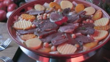 Close-up of national Kazakh dish Beshbarmak made of veggies, dough and horsemeat served in deep clay dish with hot red pepper on top