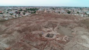 Buhara Kalesi 'nde çalışan arkeologların olduğu bir arkeolojik alan. İHA 'nın panoramayı vuruşunu kaydedip çalışan insanların üzerinden uçuyor. Bulutlu bir günde çekilmiş.
