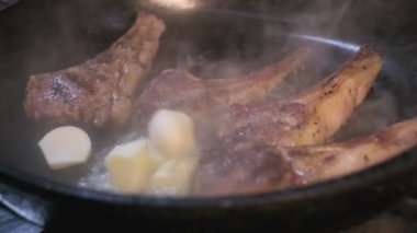 Small onions are thrown to the cast iron pan with lamb ribs fried in butter. Slow motion