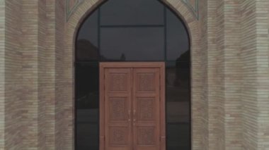 Administrative building built in the old style on the territory of the memorial complex of Bahouddin Naqshband near Bukhara. Drone cam starts filming close-up of wooden carved doors and then flies
