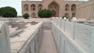 Memorial complex of Bahouddin Naqshband near Bukhara. Drone cam takes off from the walled pathway of the graveyard and flies above the complex. We see graves, mausoleum, mosque and after drone cam
