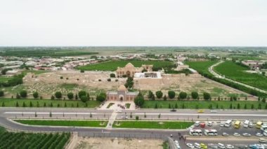 Memorial complex of Bahouddin Naqshband near Bukhara. Drone cam flies far above shooting the panorama contains higway, parking, nearby village and gardens and memorial complex. The flying camera is