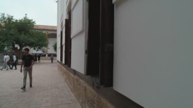 Inner-yard of memorial complex of Bahouddin Naqshband near Bukhara shoot by drone. A lot of visitors nearby. Camera flies to the stone well surrounded by oriental brickwork and ornamental tiles