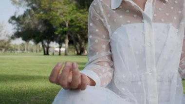 Young woman meditating doing yoga in the park on a sunny day, slow motion, close-up