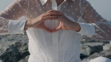 Young woman meditating doing yoga by the sea on a sunny day, slow motion, close-up