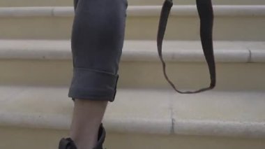 Mans legs in sneakers climb the stairs on a sunny day.