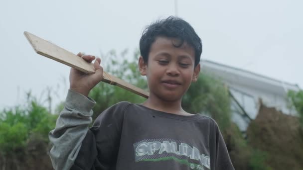 Smiling Asian Boy Simple Carved Wooden Toy Gun Front Grey — Vídeos de Stock