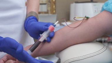 Blood sample is taken from vein by nurse wearing blue gloves
