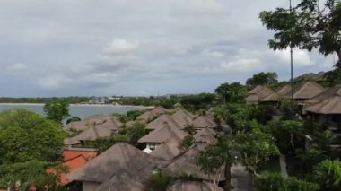 Flight of a drone over a tropical cottage village on the seashore during high tide