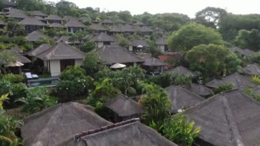 Flight of a drone over a tropical cottage village on the seashore during high tide