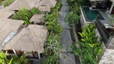Flight of a drone over a tropical cottage village on the seashore during high tide