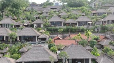 Flight of a drone over a tropical cottage village on the seashore during high tide