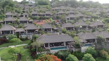 Flight of a drone over a tropical cottage village on the seashore during high tide