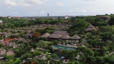 Flight of a drone over a tropical cottage village on the seashore during high tide