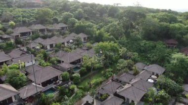 Flight of a drone over a tropical cottage village on the seashore during high tide