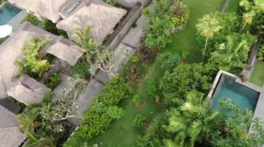 Flight of a drone over a tropical cottage village on the seashore during high tide