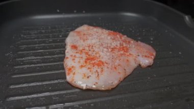 Professional chef salting chicken fillet steak, close up slow motion