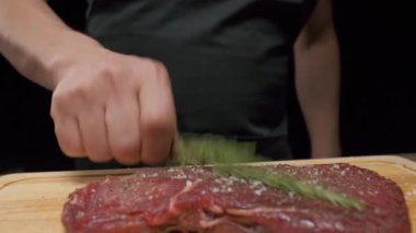 Professional chef applies greens to meat steak. Slow motion close up.
