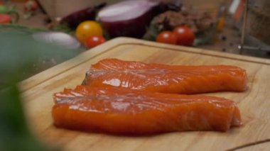 Kesme tahtasının üzerinde iki dilim somon balığı var. Ağır çekimde kapat