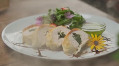 Yeşillik, çiçek süslemeleri ve yeşil yağlı bir tabakta güzelce servis edilen ıspanaklı tavuk dürümü.