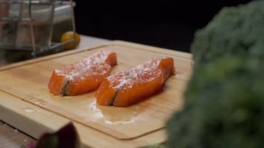 Profesyonel şef kırmızı balık bifteği tuzluyor. Yavaş çekim. Yakın çekim.