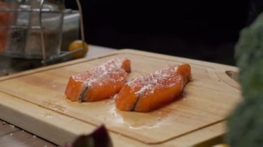 Profesyonel şef kırmızı balık bifteği tuzluyor. Yavaş çekim. Yakın çekim.