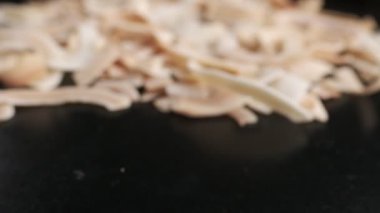 Coconut chips on a dark table close-up. Black background, slow motion.