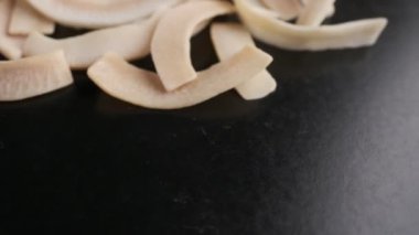 Coconut chips on a dark table close-up. Black background, slow motion.