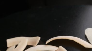 Coconut chips on a dark table close-up. Black background, slow motion.