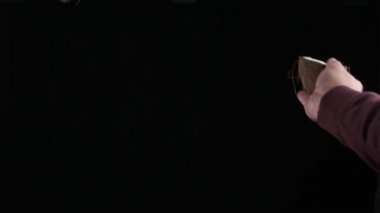 Mans hands throw up coconut cut in half on the black background. Slow motion