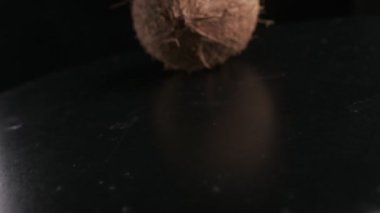 Coconut spinning on a black background, slow motion