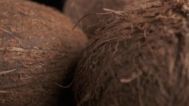Three coconuts spinning on a black background close-up, slow motion