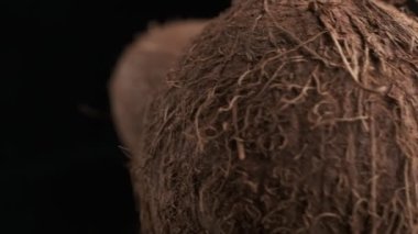 Three coconuts spinning on a black background close-up, slow motion