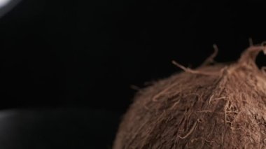 Three coconuts spinning on a black background close-up, slow motion