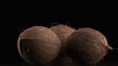 Three coconuts spinning on a black background, slow motion