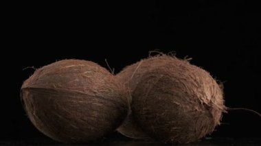 Three coconuts spinning on a black background, slow motion