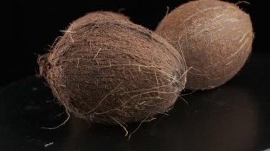 Three coconuts spinning on a black background, slow motion