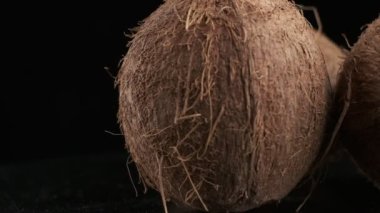 Three coconuts spinning on a black background, slow motion
