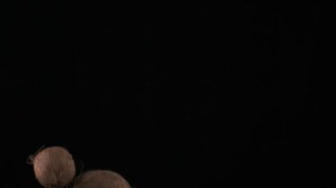 Flying up coconuts on the black background, slow motion