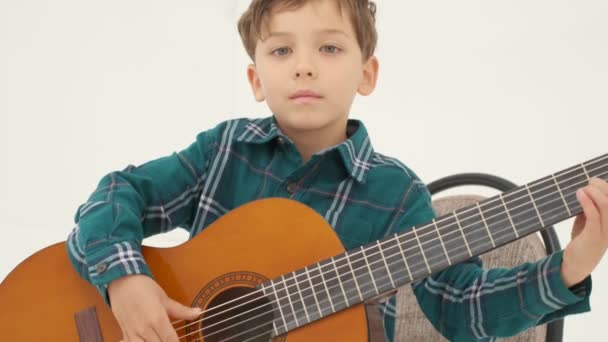 Kleiner Junge Spielt Große Klassische Gitarre Auf Dem Hocker Sitzend — Stockvideo