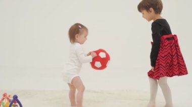 Little short hair girl plays toys with little sister wearing diaper