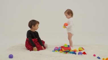 Little short hair girl plays toys with little sister wearing diaper