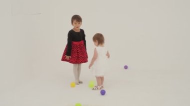 Little short hair girl plays toys with little sister wearing diaper