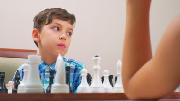 Мальчик Синей Клетчатой Рубашке Играет Шахматы Сзади Светлая Стена Крупный — стоковое видео