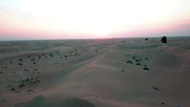 Gün batımında Dubai çölündeki kum tepelerinin üzerinden uçmak. İHA ateşi.