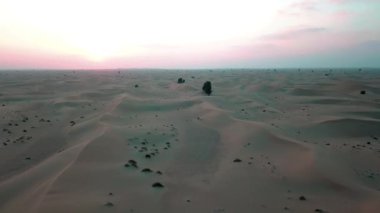 Gün batımında Dubai çölündeki kum tepelerinin üzerinden uçmak. İHA ateşi.