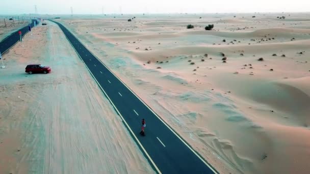 Lány Gördeszkán Lovagol Egy Sivatagi Úton Dubai Homokdűnéi Között Drónlövések — Stock videók