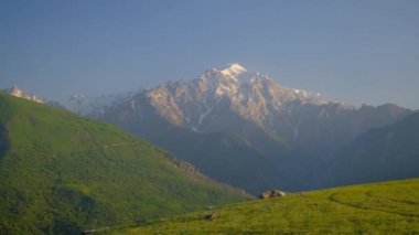 Yeşil tepeler ve karlı dağ manzarası güneşli bir günde