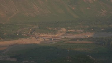 Yeşil dağlardaki sığ nehrin üzerindeki köprü.